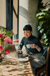 © Zamrznuti tonovi - Asian freelancer woman working remotely from coffee shop using laptop and drinking coffee