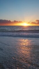 Wall Mural - stunning sunset over sea with vibrant colors reflecting on the water at the beach. vertical video