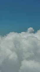 Wall Mural - flying through beautiful white fluffy clouds in blue sky. airplane travel background. vertical video