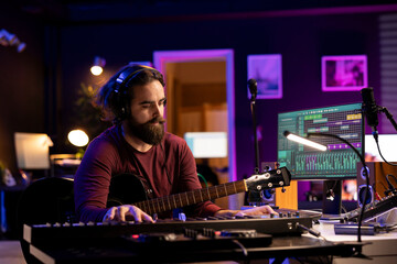 Fototapete - Skilled artist musician composing a song and playing his guitar, acoustical engineering techniques with daw software interface on computer. Producer creating music with instruments and audio gear.