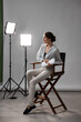 © New Africa - Beautiful woman with script sitting in director's chair in studio