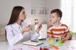 © New Africa - Speech therapist working with little boy indoors