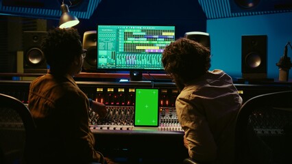 Poster - Team of producer and artist use tablet with mockup display in professional studio, mixing and mastering tracks after recording session. Experts working in control room with console. Camera B.