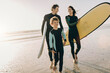 © Marko Geber - Young family of surfers walking on a beach getting ready to go surfing together on their holiday vacation