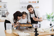 © sofiko14 - Caucasian family with male, female adults and child baking cookies in modern kitchen while recording content for a blog. Depicts atmosphere teamwork and creative food preparation for online audience.