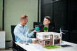 © laddawan - Experts collaborate on renewable energy solutions with house models, wind turbines, and solar panels, emphasizing green design