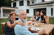 © Halfpoint - Family sitting at table and eating delicious food during spring family barbecue.