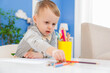 © New Africa - Little boy with colorful pencils at table indoors