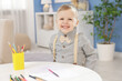 © New Africa - Little boy with colorful pencils at table indoors