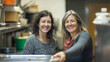 © Sabana - Two women smiling in a commercial kitchen with stainless steel and kitchen equipment in the background