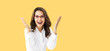 © vgstudio - Wow! Portrait image of happy expressive yelling black hair business woman raise hands, isolate yellow background with empty free text space. Gesturing cute girl wear white shirt, red eye glasses