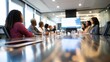 © Blackmint Studio - A multi-ethnic group of business professionals gather around a long table in a sleek conference room, actively discussing strategies while reviewing information on a large display screen