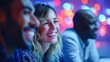 © NovaVision - Three smiling friends share a moment of joy together, lit by colorful lights.