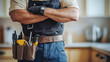 © Professional Agency - Confident handyman with arms crossed, wearing tool belt in kitchen