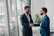 © Zamrznuti tonovi - Two businessmen shaking hands in modern office, closing a business deal