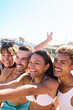 © CarlosBarquero - Vertical photo of Group of generation z friends in swimwear are happily taking a selfie on the beach, cheerful and making big smiles. Diverse young people enjoying their summer beach travel adventure