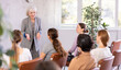 © JackF - Emotional aged female tutor leading educational class for group of women sitting in auditorium..