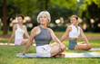 © JackF - Sedulous old lady and group of women doing spinal twist pose of yoga on mat in modern light city park together