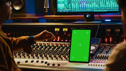 Leinwandbilder - Diverse music experts working with greenscreen on tablet and mixing console in control room, pressing key buttons and pushing sliders. Artist and producer creating a hit song in studio. Camera A.