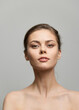 © SHOTPRIME STUDIO - Confident young woman with natural makeup, gazing directly at the camera, showcasing subtle beauty and elegance on a neutral gray background.