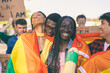 © Carlo Prearo - Happy multiethnic activists embracing with a rainbow flag at lgbtq pride parade