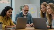 © M - Team of coworkers collaborating around a table, using laptops in the office.