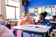 © wavebreak3 - In school, female teacher helping african american girl with classwork at desk in classroom