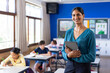 © wavebreak3 - In school classroom, holding tablet, smiling indian female teacher with students, copy space
