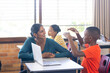 © WavebreakMediaMicro - In school, Indian female teacher with laptop engaging with students in classroom discussion