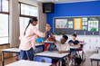 © WavebreakMediaMicro - In school, Indian female teacher giving high-five to student using tablet in classroom