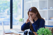 © Jirapong - Stressed young woman overwhelmed by e-learning studies at desk with laptop, notebook, headphones, hands clasped to her face in frustration