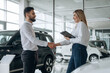 © standret - Handshake, good to meet you. Man and woman are in the car dealership