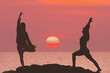 © Vladimir Razgulyaev - Women practicing yoga by the sea on a mountain in Thailand - silhouettes of two women in yoga pose against the background of an orange sunset. Yoga tours and retreats in the tropics