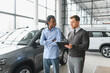 © Serhii - A consultant at a car dealership helps a customer choose a new car