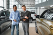 © Serhii - A consultant at a car dealership helps a customer choose a new car