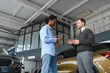 © Serhii - A consultant at a car dealership helps a customer choose a new car