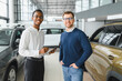 © Serhii - Car Sales Manager Showing Auto To Buyer Standing In Luxury Automobile Dealership Store