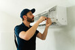 © AntonioDiaz - Technician repairing air conditioning unit with screwdriver