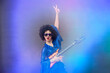 © Светлана Лазаренко - Girl comic pop star posing in black wig with toy guitar on blue background. Rock style of seventies