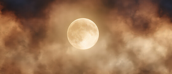 Wall Mural - A large yellow moon is in the sky above a hazy, cloudy atmosphere