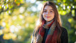© SI Creative Studio - A young woman wearing an elegant crocheted scarf stands outdoors in the park, with green trees and sunlight filtering through them. She has long brown hair and is smiling .