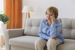 © anatoliycherkas - Sick older senior woman sit on sofa feel pain dizziness coping with morning headache concept, upset tired old woman touching sore head suffer from terrible migraine mental problem