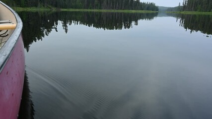 Wall Mural - View into the calm water next to a canoe of refection of a northern landscape
