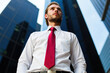 © Minerva Studio - Businessman looking up at skyscrapers in the financial district