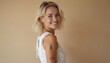 © Viktor - Smiling blond pretty girl with tattoo looking at camera. Beautiful face, healthy skin, short blonde hair. White top. Young female model at beige background. Beauty, skin care, cosmetics, cosmetology,