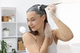 Beautiful woman dyeing her hair at home