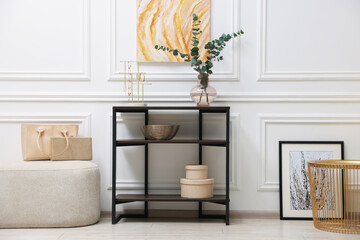 Poster - Console table with decor and pouf near white wall in room. Interior design