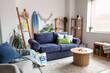 © Pixel-Shot - Interior of light living room with blue sofa, surfboard and coffee table
