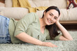 © Pixel-Shot - Young woman lying on green carpet at home