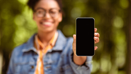 African Student Girl Showing Smartphone Blank Screen Recommending Application Standing In Park Outdoors. Mobile App Concept. Shallow Depth, Panorama